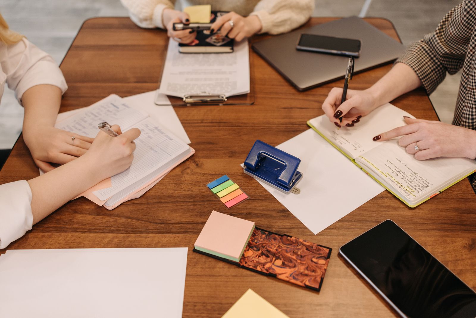 Colleagues at a wooden table taking notes from printed documents
