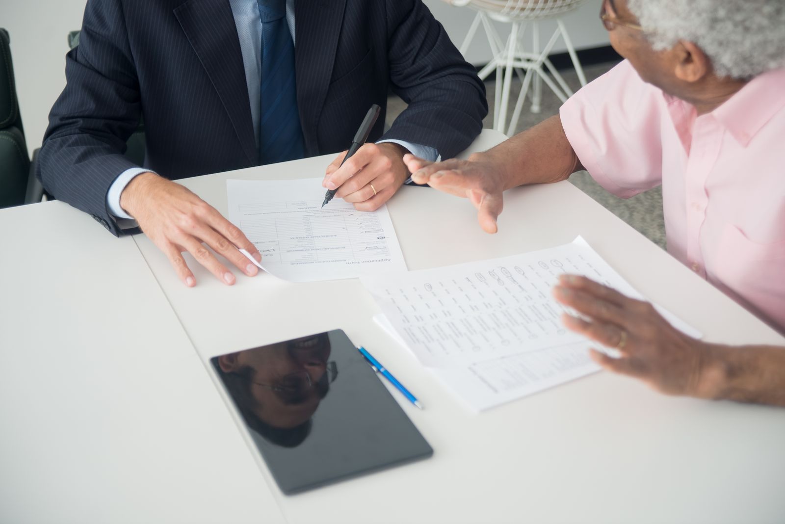 Two people going through printed schedules across a white table