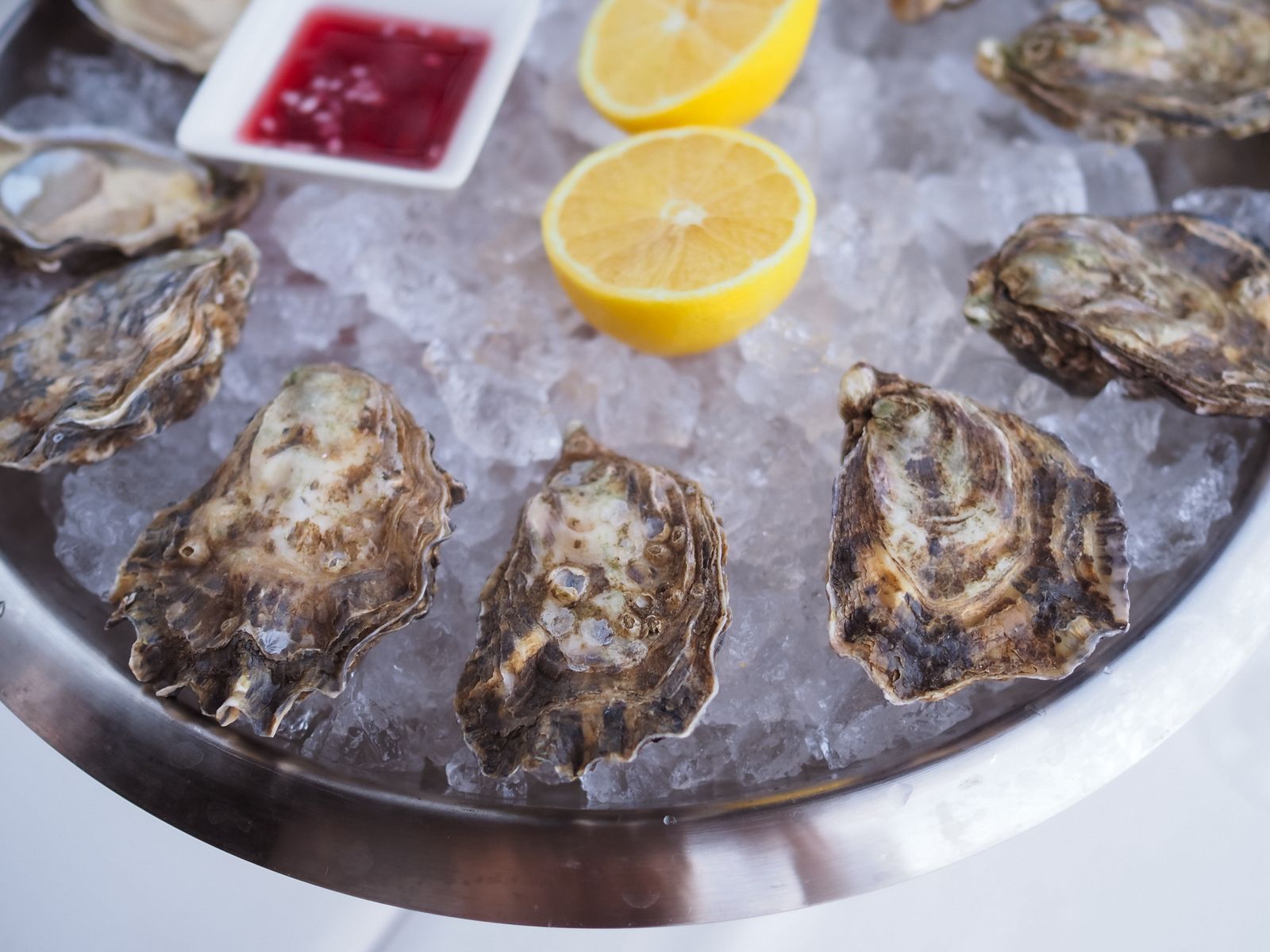 Opened oysters on ice with lemon halves and a dish of shallot vinegar