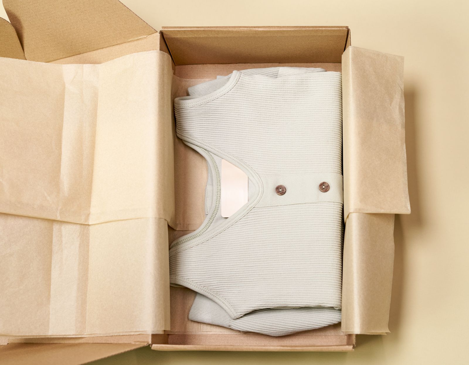 A ribbed garment folded in a cardboard box with paper