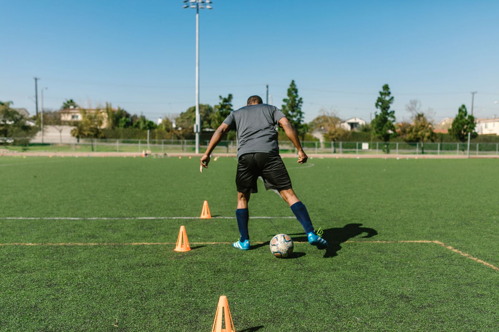 A player dribbling a ball between cones at training