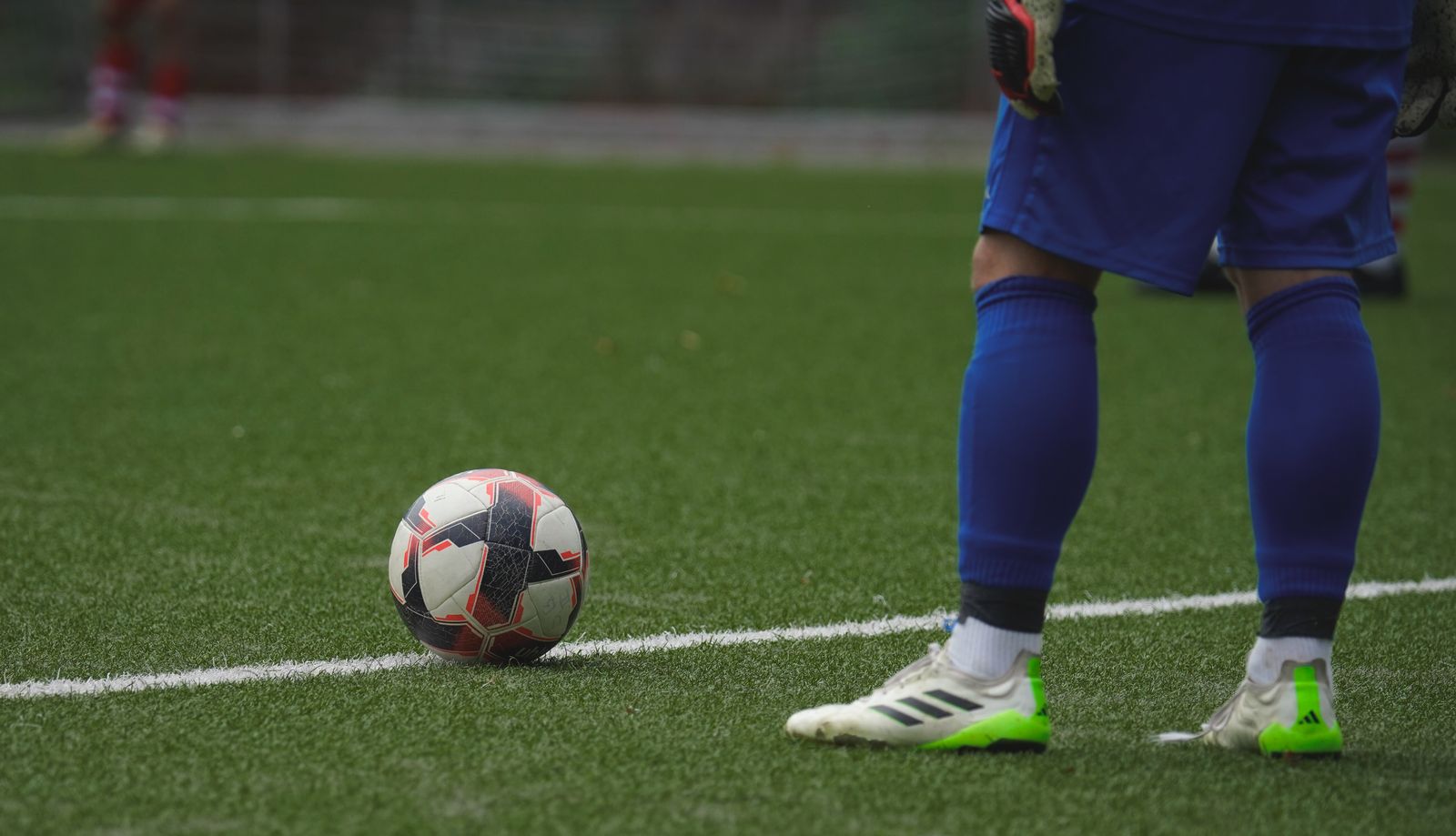 A player's boots beside a ball on the pitch