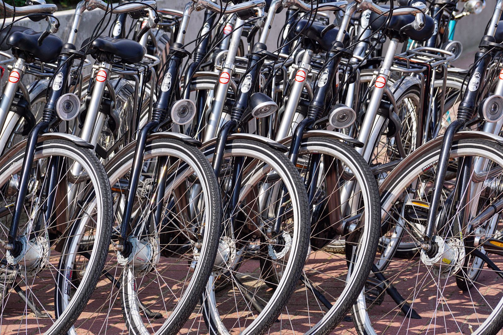 A row of parked bicycles, close up on wheels and handlebars