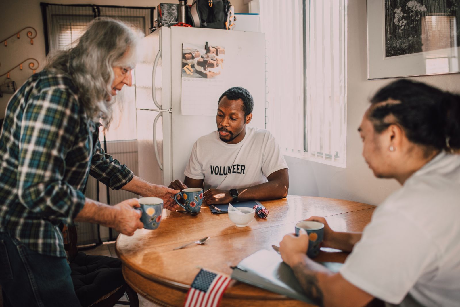 Three people talking over coffee around a kitchen table