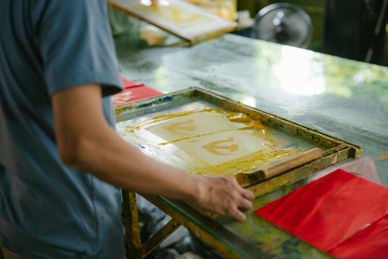 A screen-printing frame with a fresh print on the bench