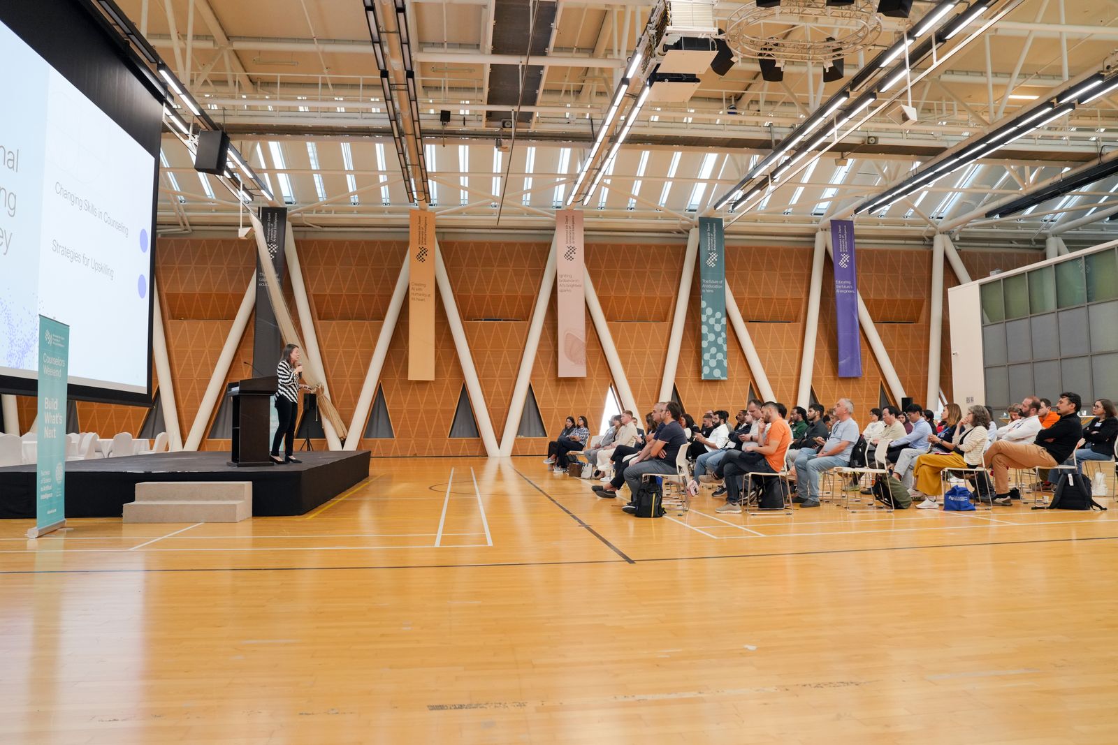 A large conference hall with an audience facing the stage