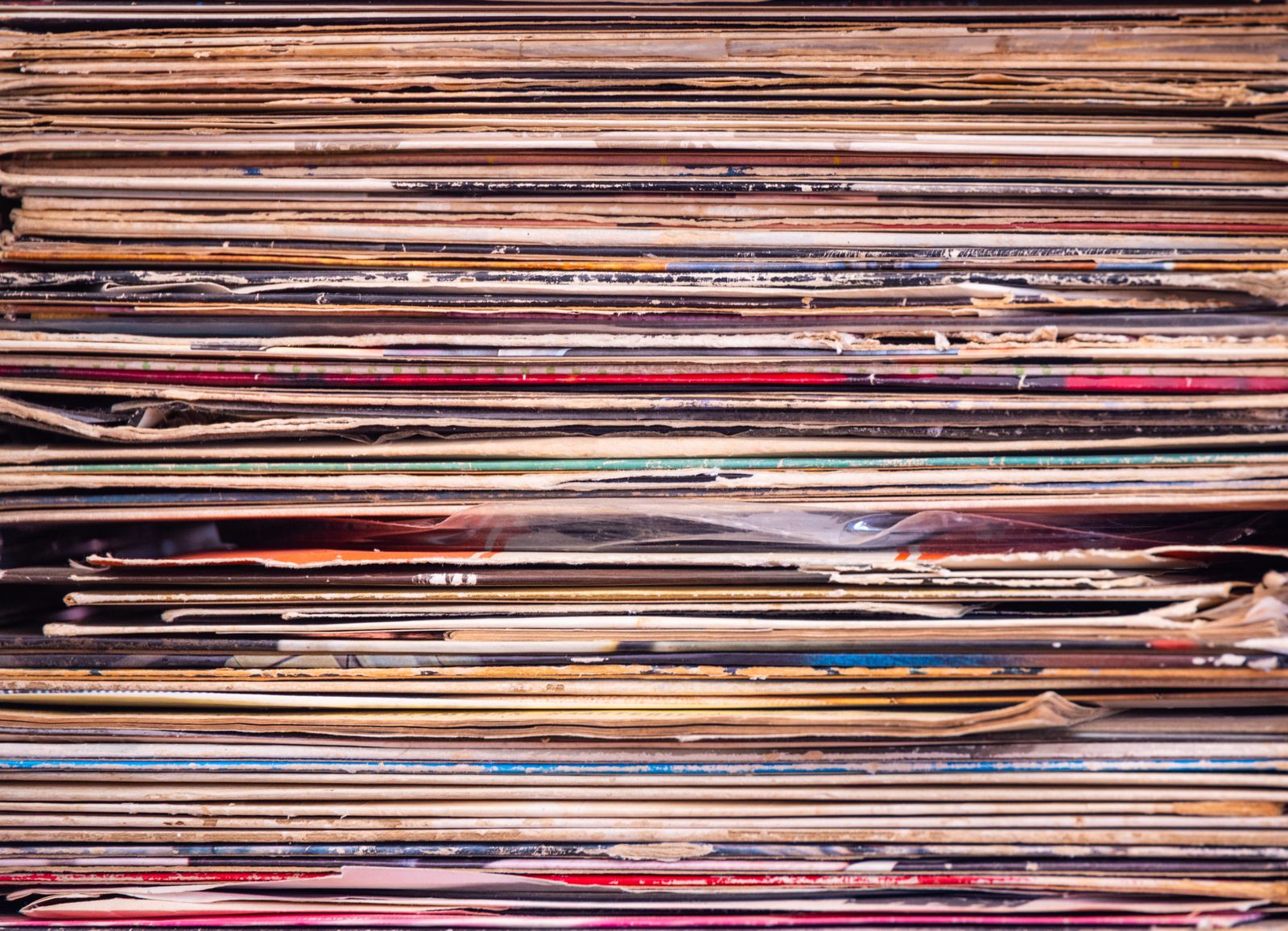 A tall stack of vinyl records in their sleeves, seen edge-on