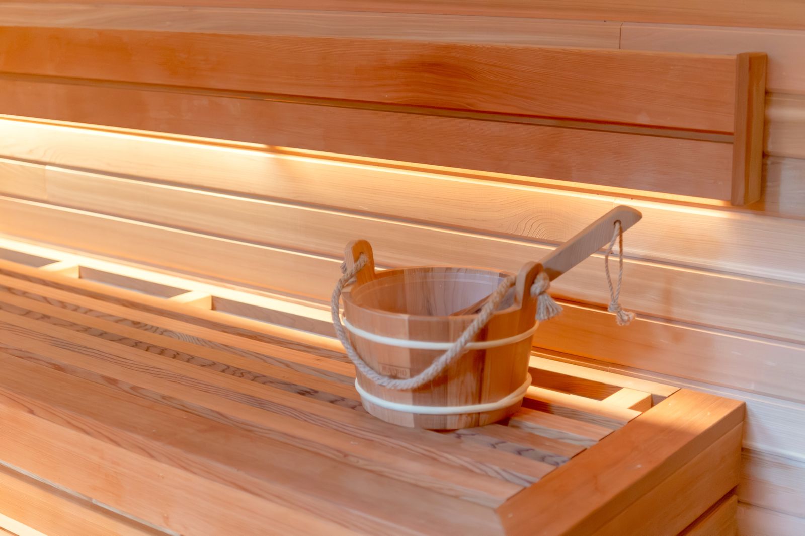 A wooden bucket and ladle on a slatted sauna bench
