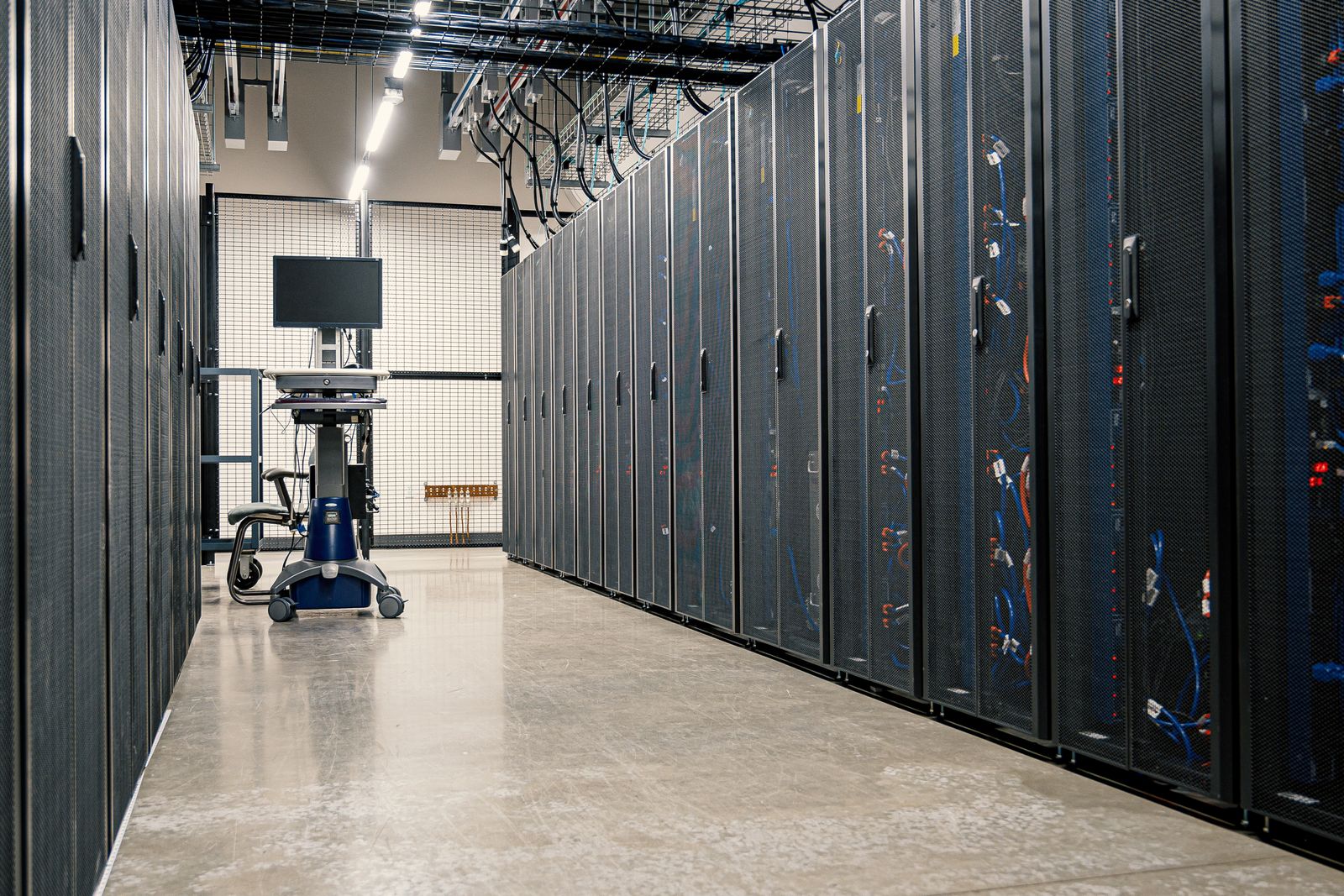 A long, bright data centre aisle between rows of black server racks