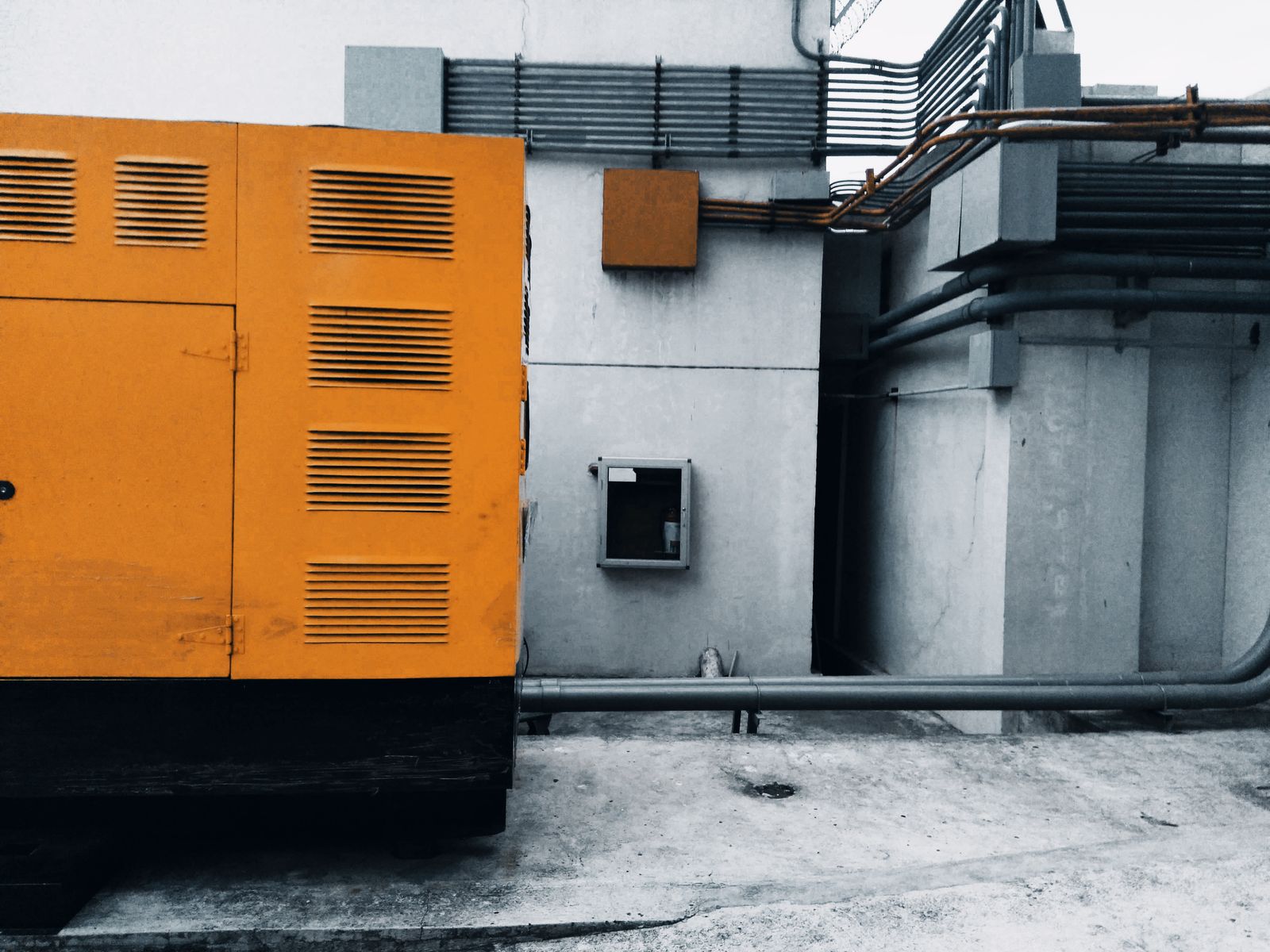 An orange standby generator housing beside a concrete building