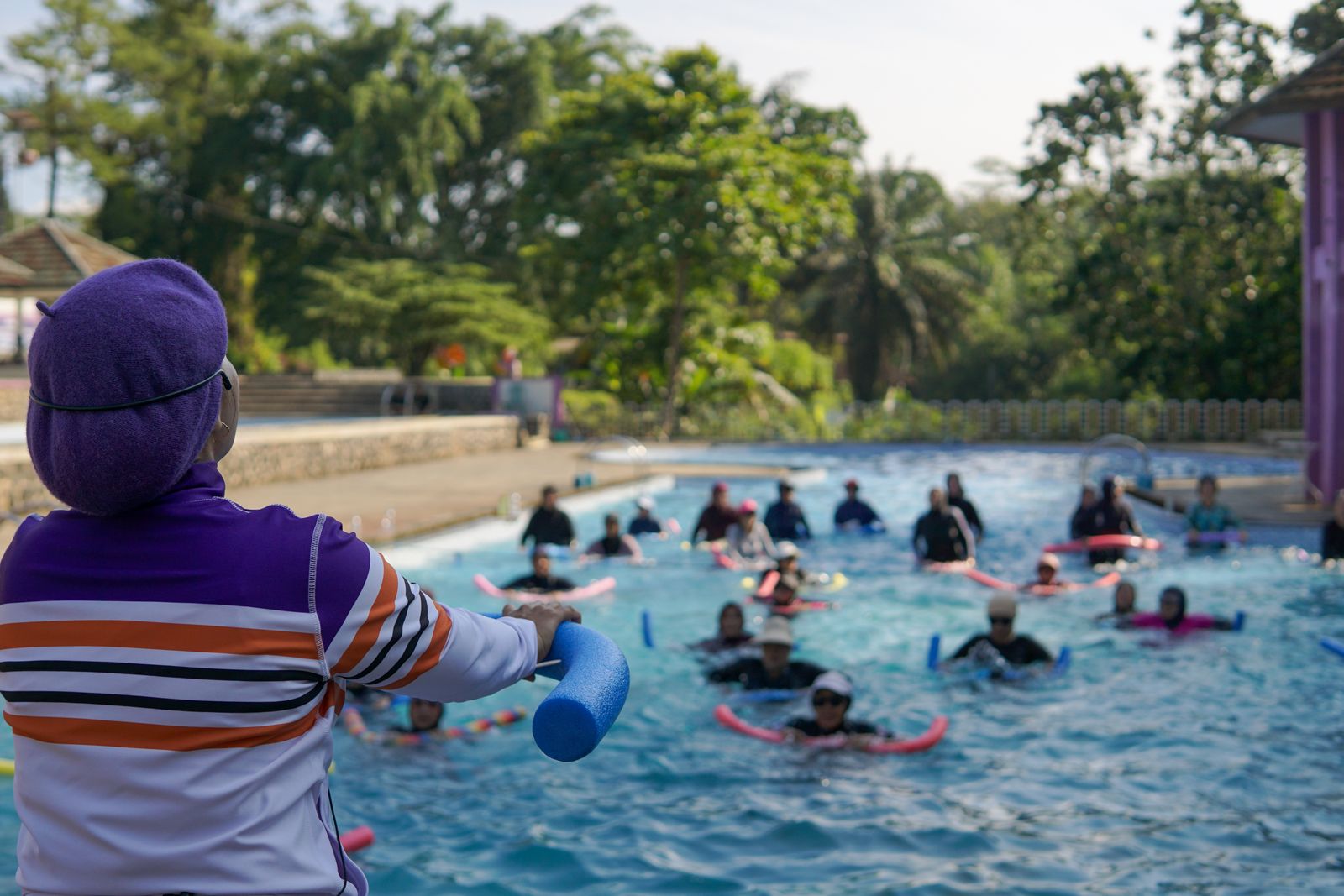 Swimming teacher on the poolside with a group of learners in the water