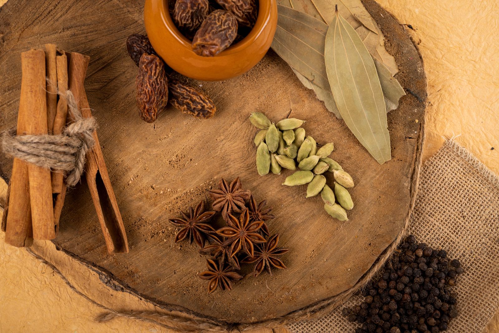 Cardamom pods, star anise, cinnamon bark, bay leaves and peppercorns on a wooden board