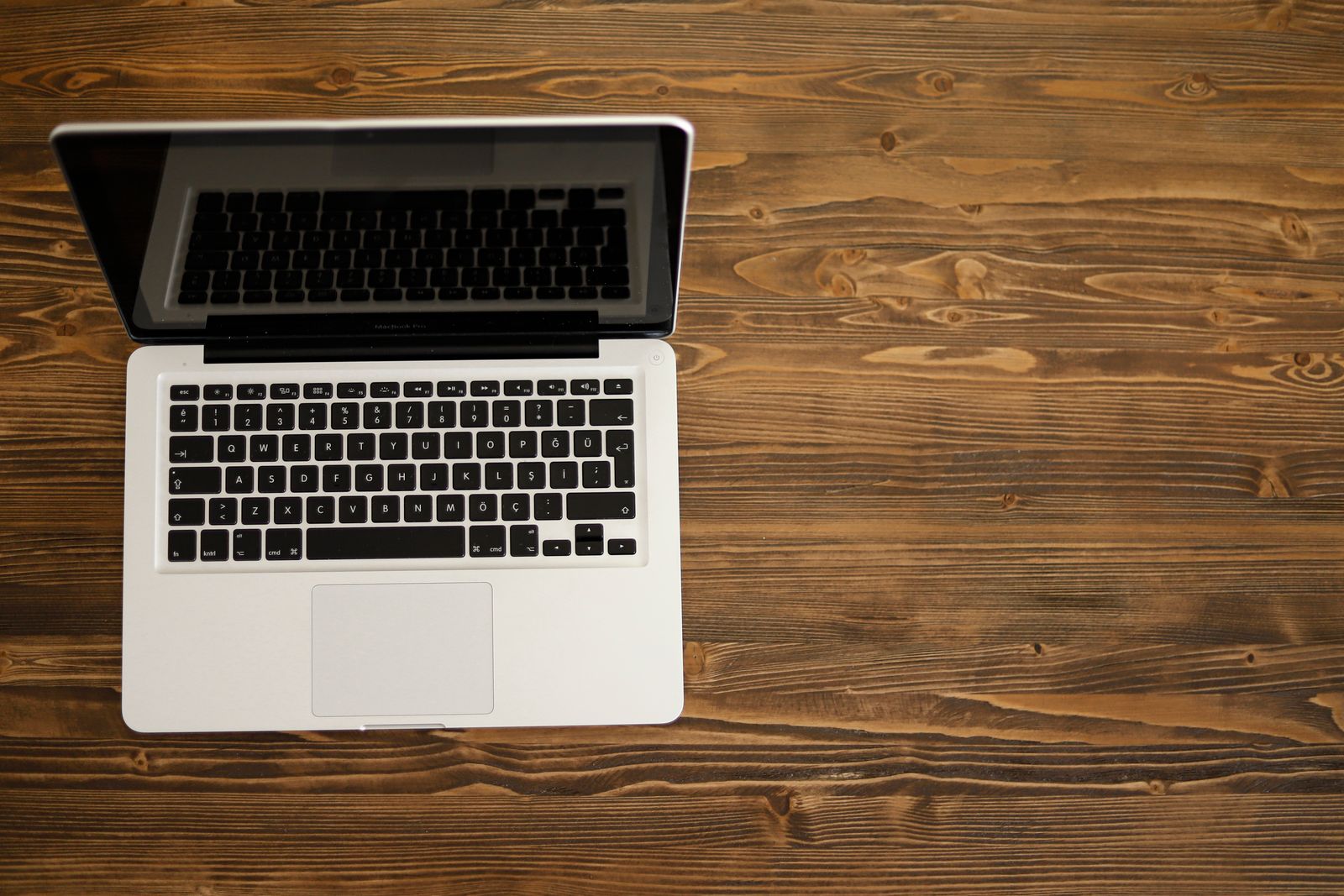 An open laptop seen from above on a dark wooden desk