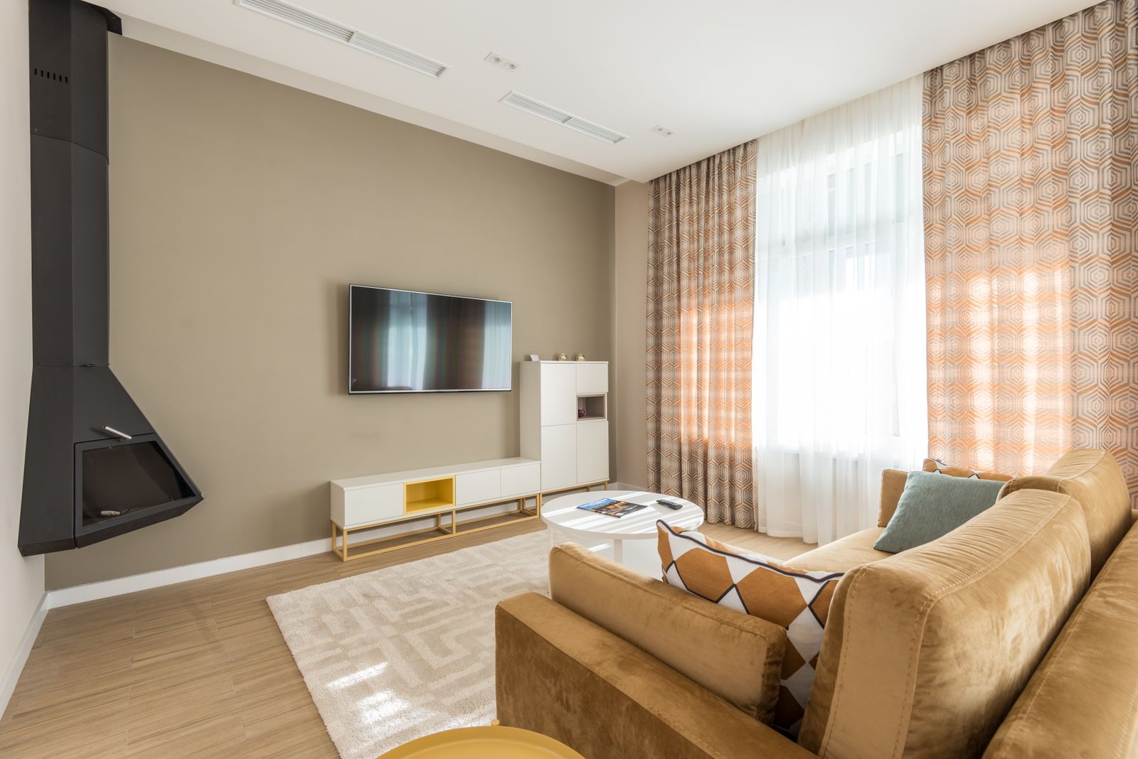 A living room with a beige sofa facing a wall-mounted TV