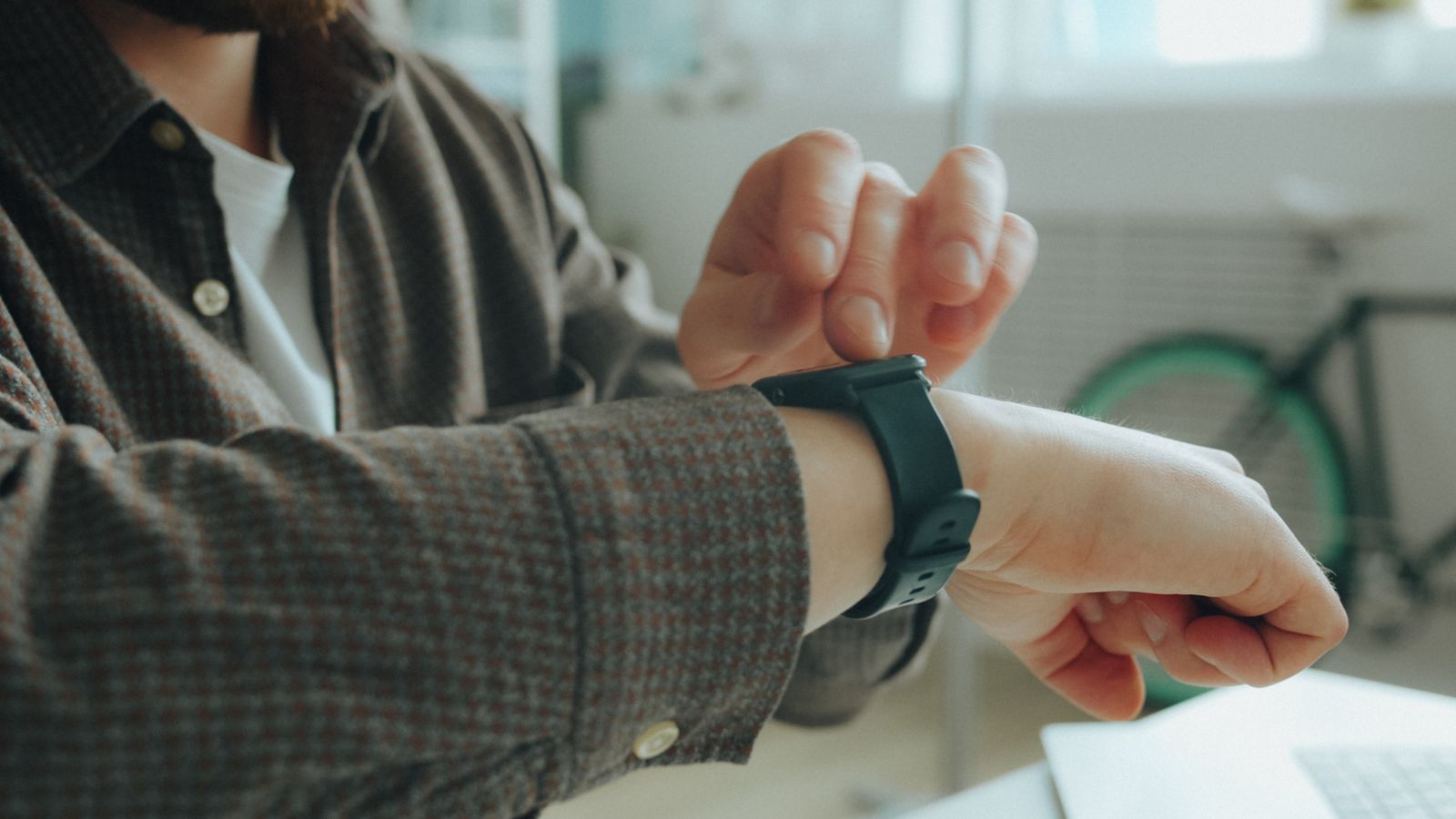 A person checking a smartwatch with a dark strap on their wrist
