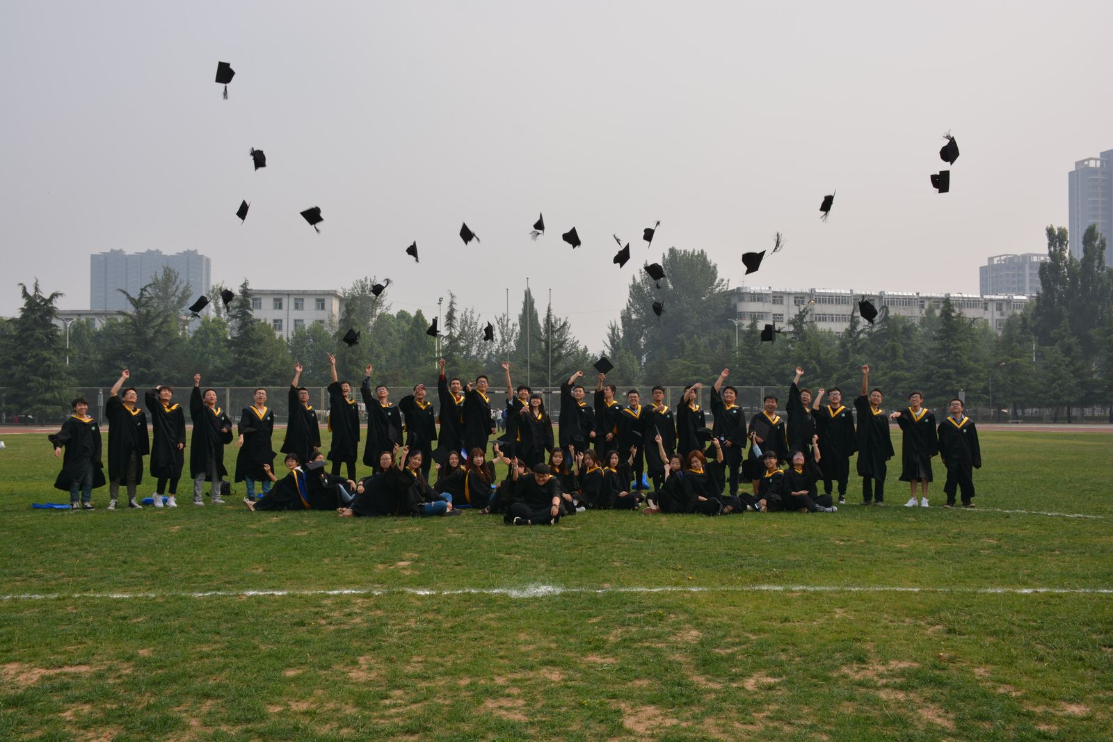 Graduates throwing their caps in the air on a lawn, seen from a distance