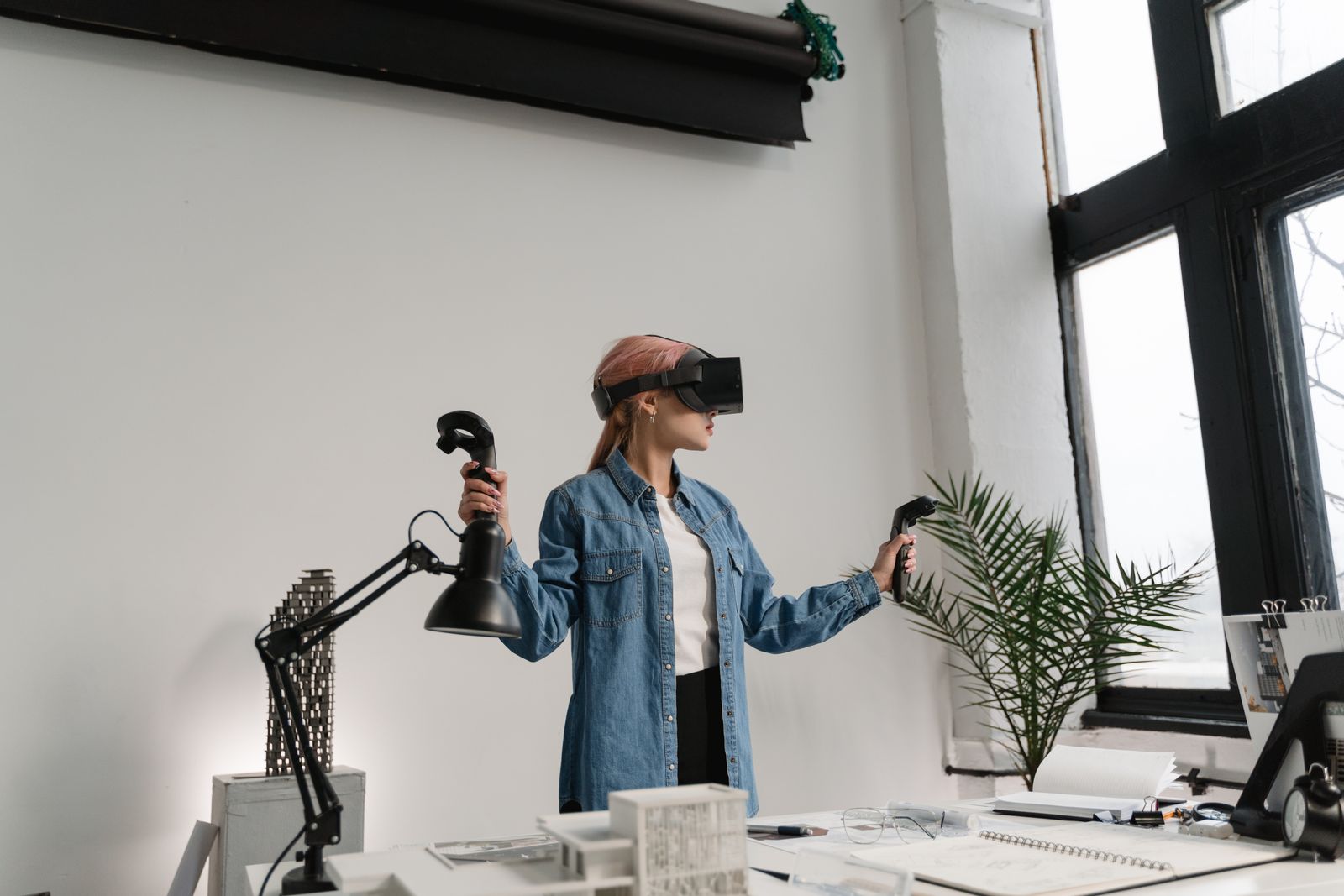 A woman in a VR headset and denim jacket testing a build in an office
