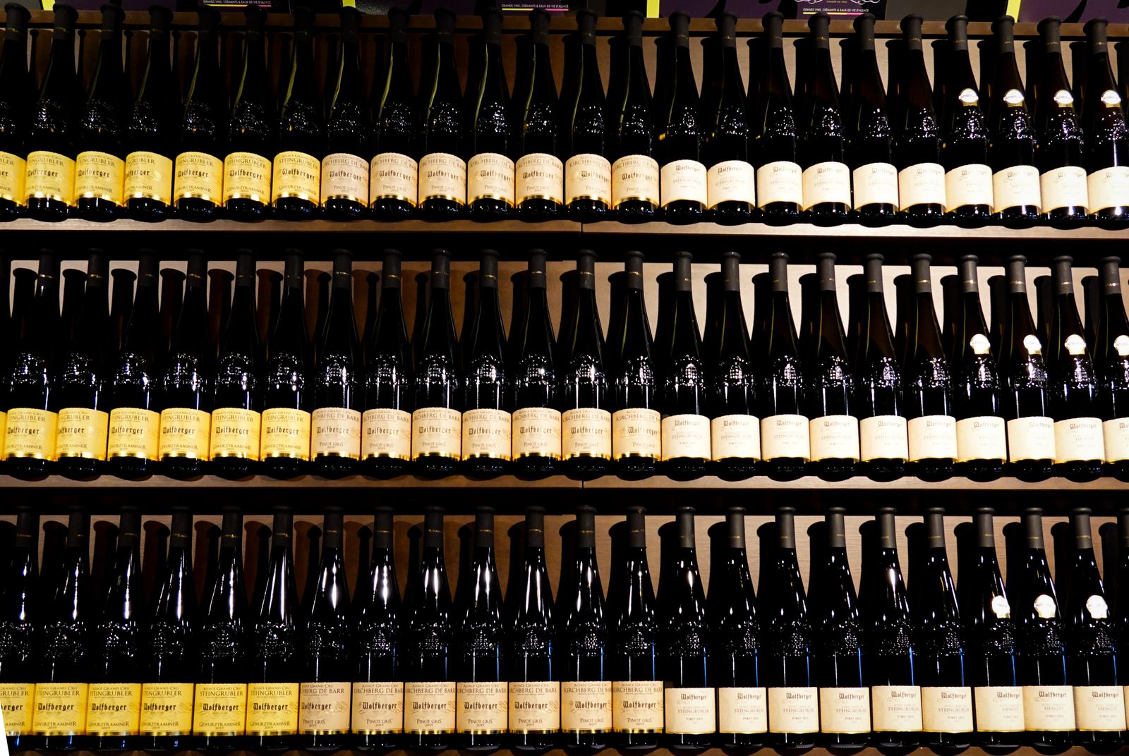 Rows of wine bottles standing on shop shelves